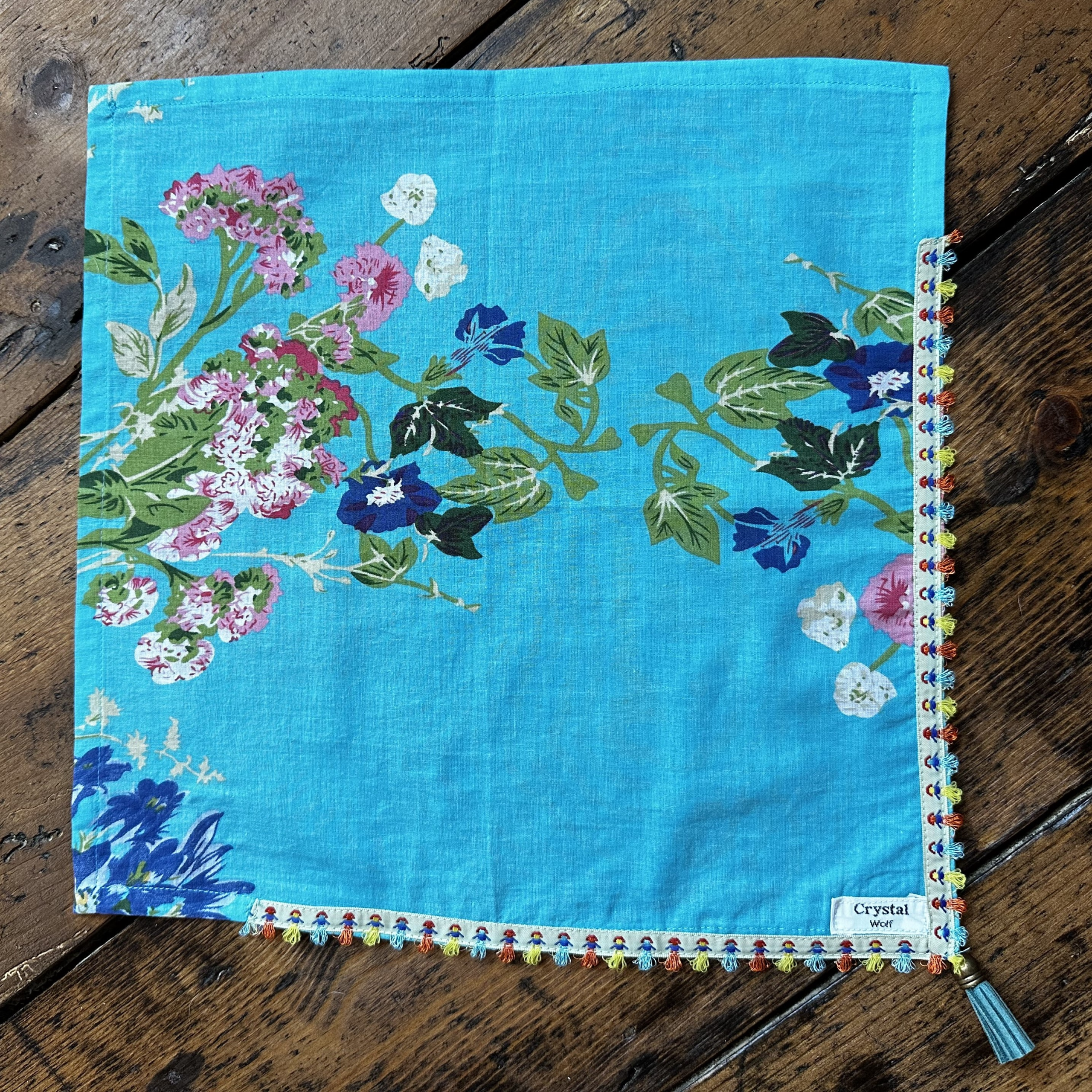 “Turquoise floral dog bandana with ribbon trim and tassel.