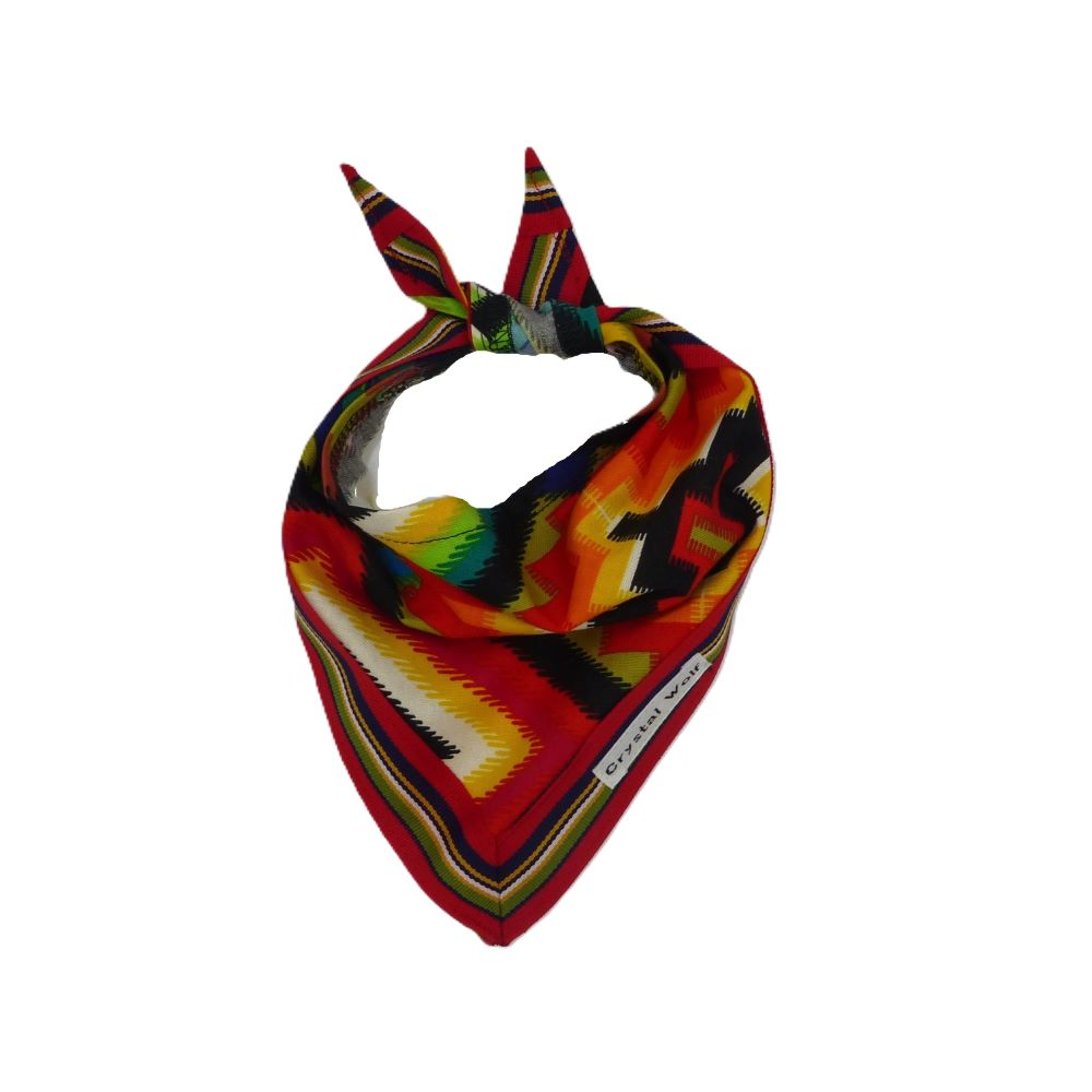 Colorful Mexican print dog bandana with ribbon edging, displayed lying flat on a surface